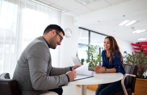 HR representative smiling as a man signs a contract