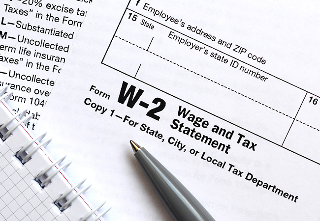 Form W-2 Wage and Tax Statement shown with a pen nearby, ready for tax filing.
