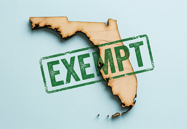 Workers Comp Exemption in Florida - PEOPayGo - PEOPayGo Wooden cutout of the state of Florida with a green EXEMPT stamp laid across it.